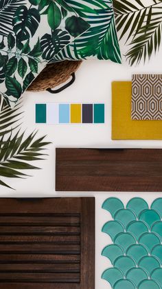 some green leaves and other items on a white surface with color swatches in front of them