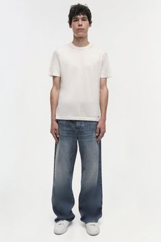 PRE-FALL 2024 MEN'S COLLECTION The Poe Jeans in Vintage Wash. Featuring a relaxed fit through the hips and thighs, these jeans flare out to a wide leg for an effortlessly cool and contemporary look. This classic design and versatile wash make them a stylish addition to any wardrobe. Mens Jeans And T Shirt Style, White Tee And Jeans, College Au, Model Style, T Shirt Style, Knitwear Tops, Jeans Flare, Fall 2024, Shop Swimwear