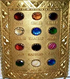 an ornate gold plate with nine different colored glass jewels on it's front and sides