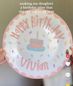 a person holding up a plate with a birthday cake on it