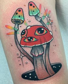 an artistic tattoo design on the arm of a woman's leg, featuring a red mushroom