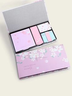 a pink and grey box with four different colored cards in the front, on top of a white background