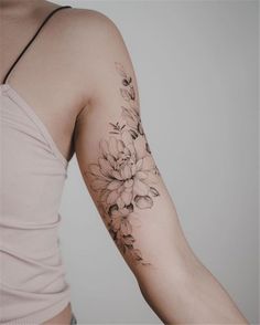 a woman's arm with flowers on it and a tattoo that is black and white