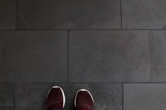 a pair of red shoes sitting on top of a black floor next to a white umbrella