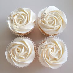 four cupcakes with white frosting and crystal decorations on them are arranged in the shape of a rose