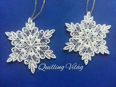 two white snowflakes hanging from strings on a blue background with the words quilting vista written below