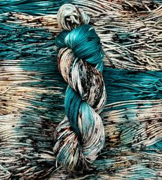 a skein of yarn sitting on top of a piece of wood with blue and brown stripes