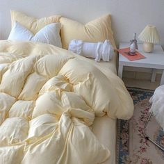 an unmade bed with pillows and blankets on it in a bedroom next to a table