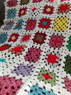 a crocheted blanket with many different colors and shapes on the bottom, including flowers