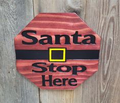 a wooden sign with santa's hat on it that says stop here