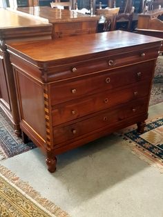 a wooden dresser sitting on top of a carpeted floor next to a table and chairs