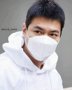 a man wearing a white mask and hoodie looks off to the side while looking at the camera