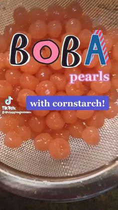 a bowl filled with lots of orange candies on top of a wooden table next to a sign that says boba pearls