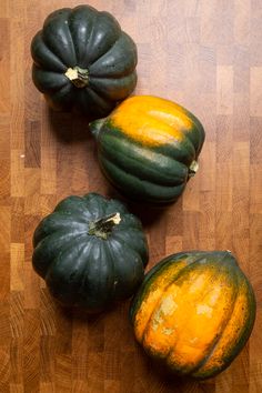 three green and yellow pumpkins on a wooden surface