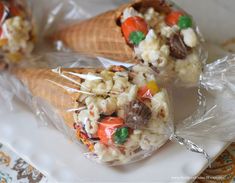 two cones filled with candy corn and marshmallows on top of a white plate