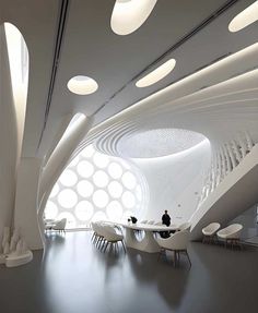 the interior of an office building with white walls and circular lights on the ceiling, along with chairs and tables