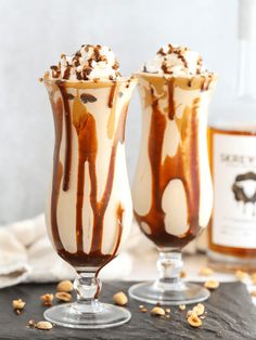 two glasses filled with ice cream and caramel drizzle on top of a table