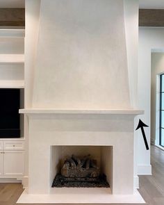 a fireplace in a living room with white walls and wood flooring on the other side