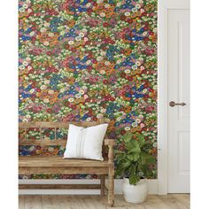 a wooden bench sitting in front of a wall covered in colorful flowered wallpaper