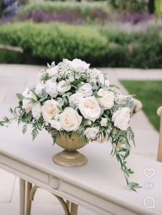 a vase filled with white flowers sitting on top of a table next to a chair