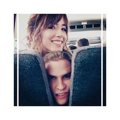 two people sitting on a bus with their faces close to each other and looking at the camera