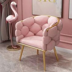 a pink chair with a gold frame and a flamingo standing next to it