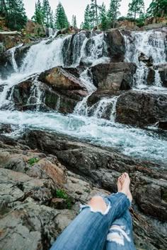 a person laying on rocks next to a waterfall