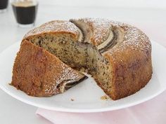 a sliced cake on a white plate next to a cup of coffee