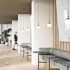 an empty waiting area with benches and lights hanging from the ceiling, while a person walks by