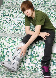 a young man sitting on top of a white and green tiled floor next to a skateboard