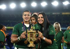 a man and woman holding a trophy in front of a crowd at a sporting event