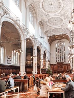 people sitting at tables in a large church with high ceilings and chandeliers hanging from the ceiling