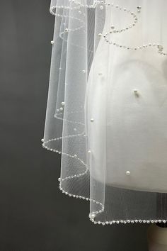 three tiered white veils with pearls hanging from the side on a mannequin