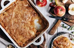 an apple cobbler is sitting on a table with apples