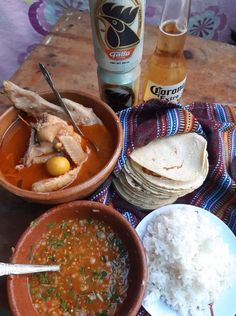 a table topped with bowls of food next to bottles of booze and rice on top of a wooden table