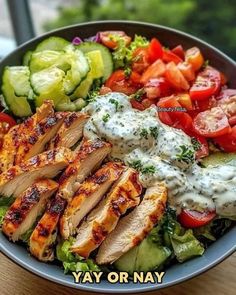 a salad with chicken, tomatoes, cucumbers and dressing on it in a bowl