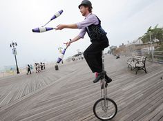 a person riding a bike on a boardwalk with two long sticks in the air above their head