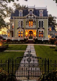 a large green house with lots of windows on it's front porch and gate