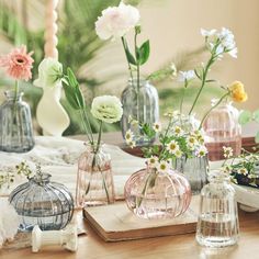 several glass vases with flowers in them on a table