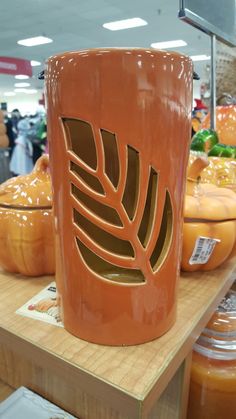 an orange coffee mug sitting on top of a wooden table in front of pumpkins