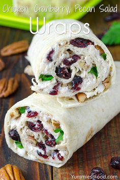 two wraps filled with chicken, cranberries and pecans on top of a wooden table