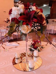 a centerpiece with flowers and candles sits on a table in a banquet room at a wedding