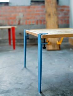 two tables with different colored legs in front of a brick wall, one is made from plywood and the other is painted blue