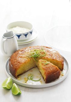 a cake on a plate with a slice cut out and some limes next to it