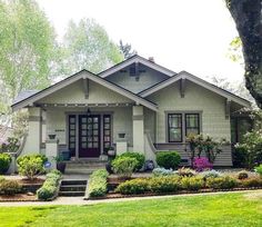 a house that is in the middle of some grass and flowers on the front lawn