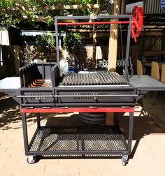 an outdoor bbq grill with wheels on the side and tables in front of it