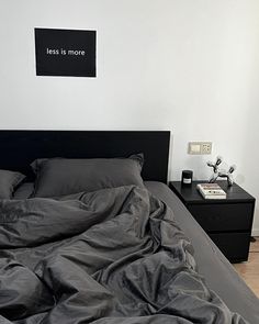 an unmade bed with black sheets and pillows