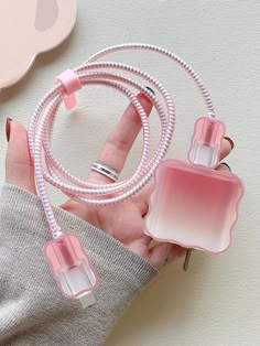 a woman holding two pink and white perfumes in her hand next to a heart shaped object