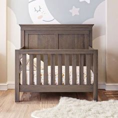 a baby's room with a crib and wall mural