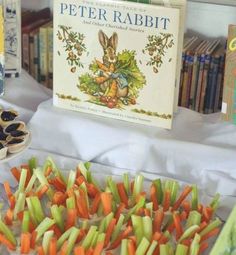 there are many different foods on display at the table and in front of them is a book about peter rabbit